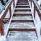 Square Focus on stairs with grate treads and metal handrails against snow covered hill