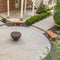 Square frame Aerial view of benches and fire pit on circular paved patio outside a building