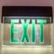 Square frame Building interior with a neon green light Exit sign pounted on the white wall