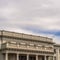 Square frame Building with white wall balcony and security camera on roof against cloudy sky