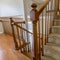 Square frame Carpeted staircase with brown handrail inside a house with shiny wooden floor
