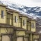 Square frame Close up of facade of townhomes with snowy mountain and cloudy sky background