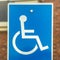 Square frame Close up of Handicapped Parking sign against blurred red brick wall of church
