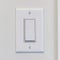 Square frame Electrical rocker light switch with flat broad lever on white interior wall