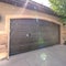 Square frame Exterior of a home with wide arched garage door against bright sunlight and sky