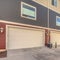 Square frame Exterior of three storey townhomes with garages and red gray and beige walls