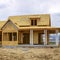 Square frame Facade of home under construction against snowy mountain and cloudy sky