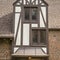 Square frame Gabled dormer with decorative windows against brick wall and roof of building