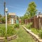 Square frame Garden with lush plants and childrens playground under blue sky on a sunny day