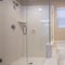 Square frame Glass walled shower stall and shiny bathtub inside the bathroom of a home