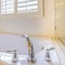 Square frame Gleaming built in bathtub and window with blinds inside a bathroom