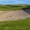 Square frame Golf course with sand bunker and vibrant fairway under blue sky on a sunny day