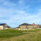 Square frame Grassy terrain and houses under blue sky with white clouds on a sunny day