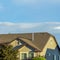 Square frame Gray roof of sunlit home with vast cloudy blue sky background on a sunny day