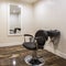 Square frame Hairdresser chair and backwash shampoo bowl inside salon with bench and mirror