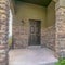 Square frame Home exterior with pillars and railing at the front porch and brown wooden door