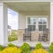 Square frame Home facade with stairs leading to porch with pillars and gray door with wreath