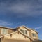 Square frame Home with front gable roof and dormers against vast blue sky with clouds