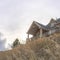 Square frame Home at neighborhood sitting on top of hill gainst snowy mountain and cloudy sky