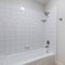 Square frame Interior of a bathroom with toilet bowl and alcove bathtub shower combo with tiles