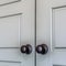 Square frame Matte black round door knobs of a double door with paneling inside a home