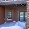 Square frame Mountain home facade with balcony over double glass doors and snowy entrance