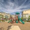 Square frame Pathway around childrens playground against townhomes and cloudy blue sky