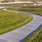 Square frame Pathway curving through a lush grassy terrain lit by sunlight on a sunny day