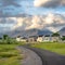 Square frame Paved road that curves through a field with multi storey homes in the distance