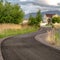 Square frame Paved road with yellow traffic delineator posts winding through a grassy field