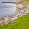 Square frame Picturesque lake scenery with wooden deck and rocks on the grassy shore