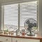 Square frame Potted cacti and electric fan on wooden cabinet against bay window of a home