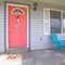 Square frame Red front door of house with blue porch chairs against windows with shutters