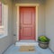 Square frame The red front door of a house with concrete exterior wall and shutters on window