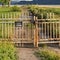 Square frame Rusty gate chain link fence and dirt road on a grassy field in front of a lake