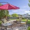 Square frame Seating area on a stone patio under the shade of a red umbrella on a sunny day