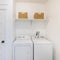 Square frame Small white laundry room interior with washer and dryer unit beside a narrow white door