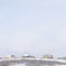 Square frame Snow covered hill top with snowy houses against vast cloudy sky in winter