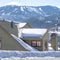 Square frame Snow covered pitched roof top of home against blurry mountain and sky in winter