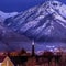 Square frame Snowy Wasatch Mountain towering over downtown Provo against blue evening sky