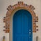 Square frame Stairs leading to the vibrant blue arched door at the entrance of a home