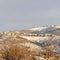 Square frame Sunlight beaming down on snow covered hills with houses built on gentle slopes