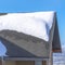 Square frame Sunlit gray pitched roof of a home with mound of fresh snow at winter season