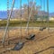 Square frame Swings at a playground casting shadows on the ground on a sunny day