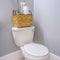 Square frame Toilet at the corner of a bathroom with a rattan basket on top of the tank
