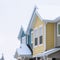 Square frame Townhome exterior with snowy gable valley roof against overcast sky in winter