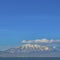 Square frame Vivid blue sky with puffy clouds over a snow peaked mountain and calm lake