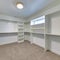 Square frame Walk in closet of house with empty built in shelves and two levels clothing rods