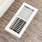 Square frame White air conditioner duct grille cover against floor with brown carpet