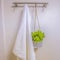 Square frame White towel and ornamental plant hanging on a wall rod inside a bathroom